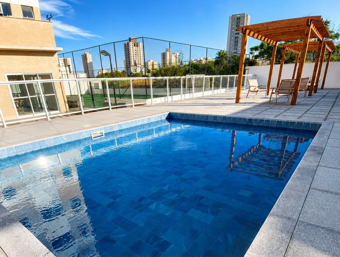 Área comum de condomínio limpa e conservada com piscina e espaços de convivência